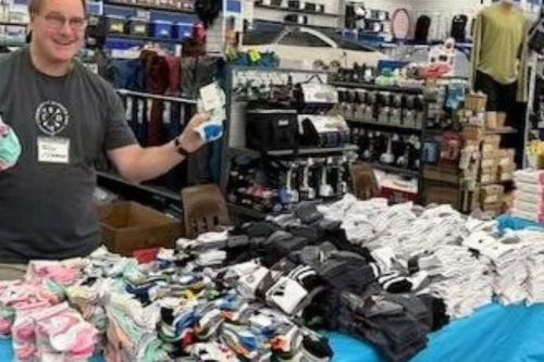 A man holds up a pair of socks at a socks and shoes donation drive for local low-income schoolchildren in Spokane, WA.