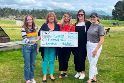 Five women hold up a check for $1,000 from the Windermere Oregon Coast offices to local organization SMART Reading.