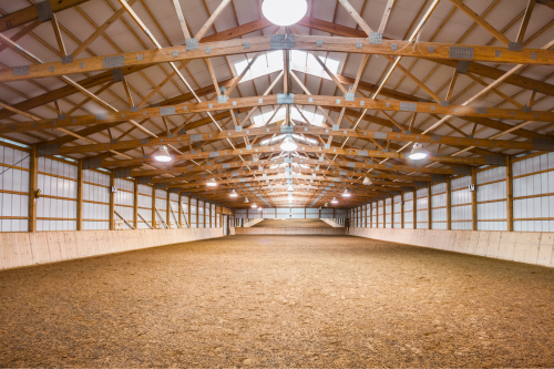 The inside of a large enclosed riding arena on an equestrian property.